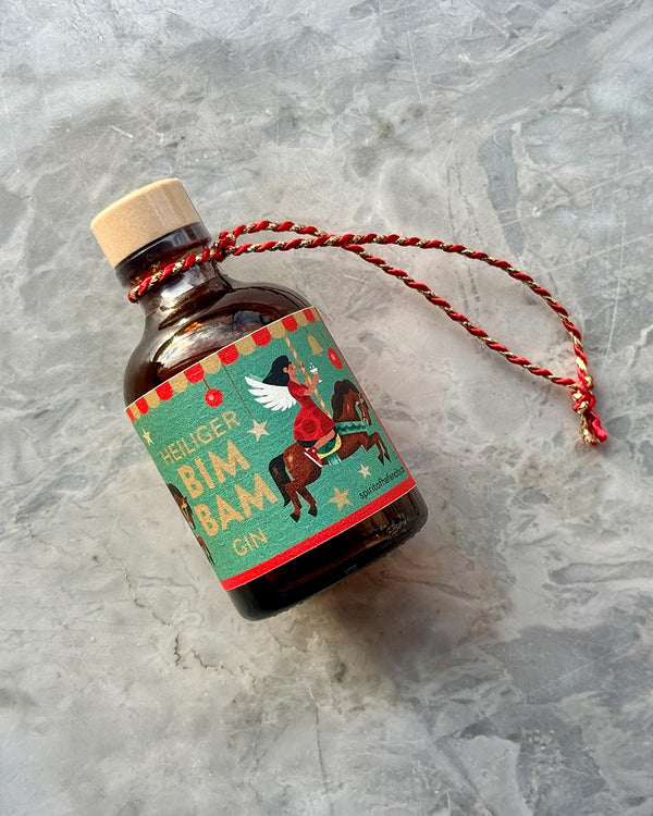 Heiliger Bimbam Gin 43% Vol. in kleiner, dunkler Glasflasche mit festlichem Etikett und roter Kordel, ideal als Weihnachtsbaum-Dekoration.