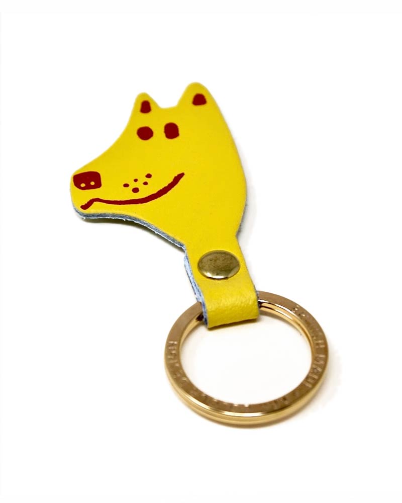 Dog Schlüsselanhänger Yellow aus Leder zeigt einen cartoonhaften Hundekopf mit roten Markierungen, goldfarbenem Schlüsselring und Druckknopf. Hergestellt in Schottland von Ark Colour Design.