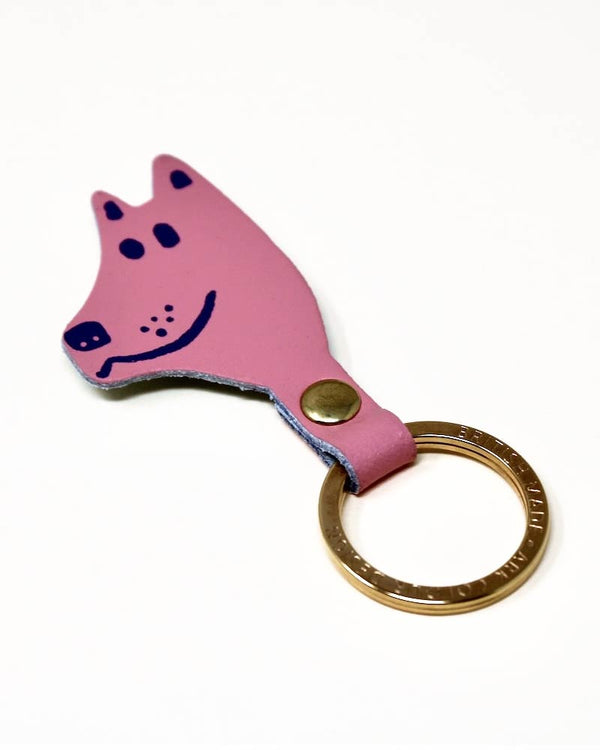 Schlüsselanhänger Dog aus echtem Leder in Hellrosa, gestaltet als stilisierter Hundekopf mit handgezeichnetem Gesicht, goldfarbenem Ring und Messingniete, hergestellt von Ark Colour Design.