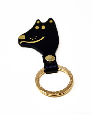 Schlüsselanhänger Dog Black aus schwarzem Leder, Hundekopf-Form mit goldenen Details, verbunden mit einem goldfarbenen Schlüsselring. Hergestellt in Schottland von Ark Colour Design.