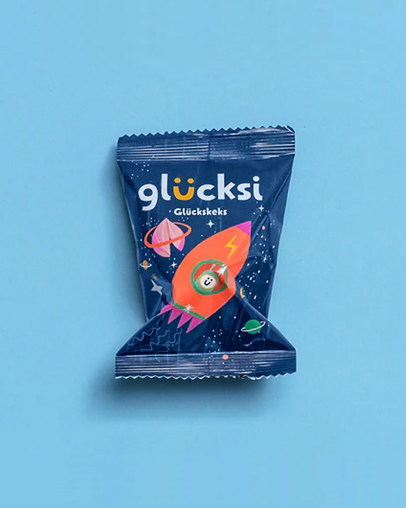 glücksi - der Glückskeks für Kinder: Einzelverpacktes Snackpaket mit Weltraummotiv, enthält einen Glückskeks mit geheimen Botschaften, ideal für kindliche Freude und Überraschung.