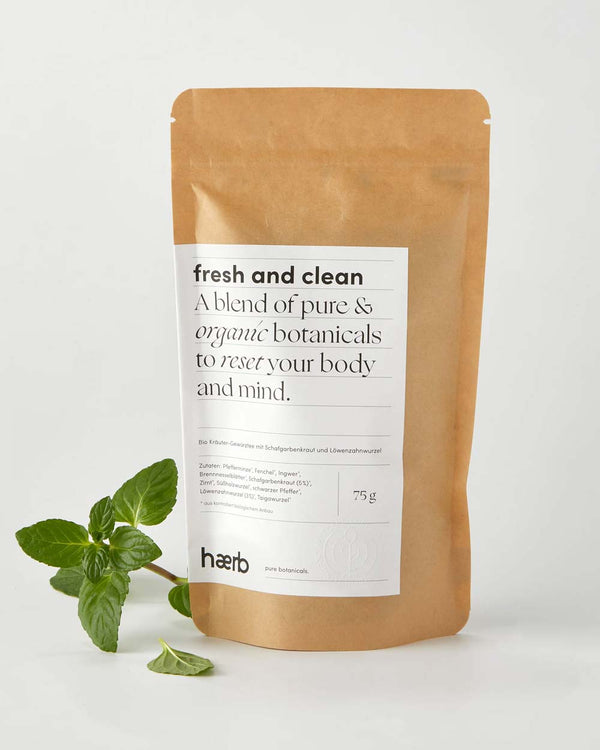 Haerb Bio Teemischung Fresh & Clean in 75g Kraftpapierbeutel, enthält Pfefferminze, Schafgarbenkraut und Löwenzahnwurzel, mit frischen Minzblättern daneben.