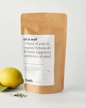 Haerb Bio Teemischung All Is Well - Zitronengras und Ingwer in brauner Kraftpapiertüte, daneben eine Zitrone und lose Teemischung.