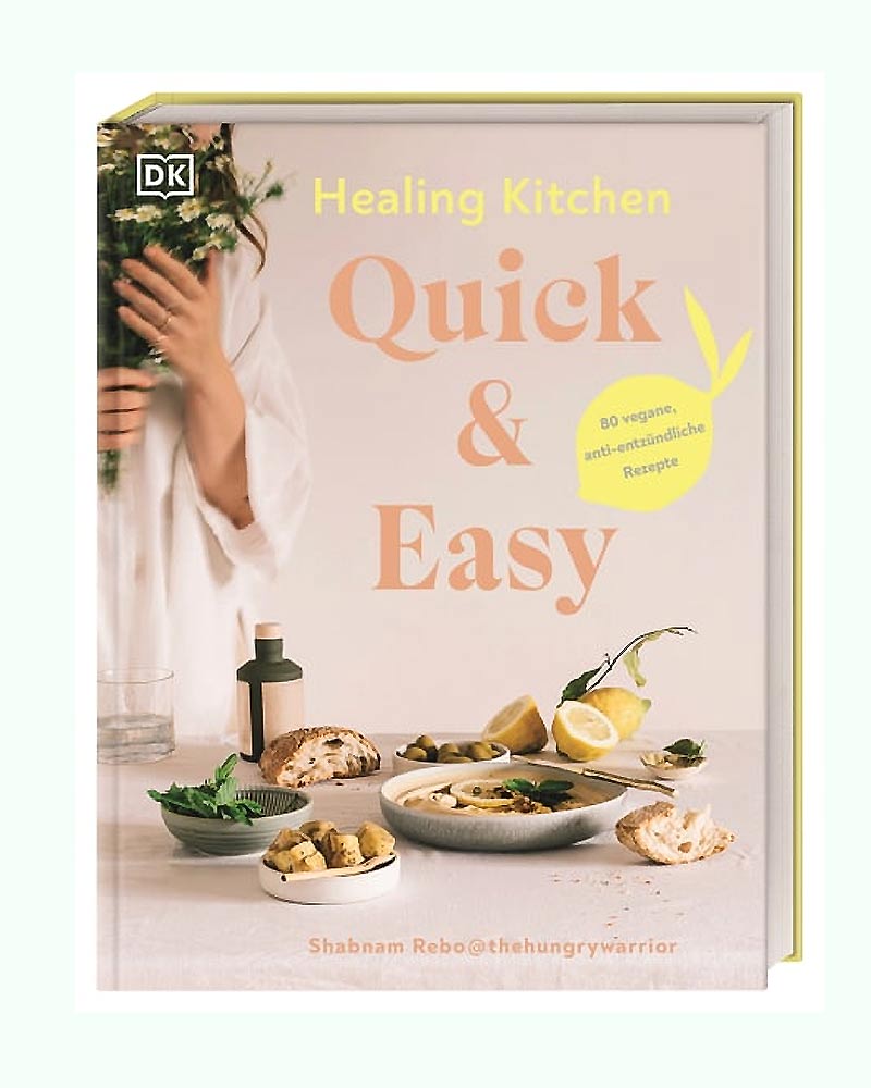 Healing Kitchen Quick & Easy - 80 vegane antientzündliche Rezepte: Kochbuch-Cover mit Tischszene, Suppenschüssel, Brot, Oliven, Zitronen, Kräutern und Blumen im Hintergrund.