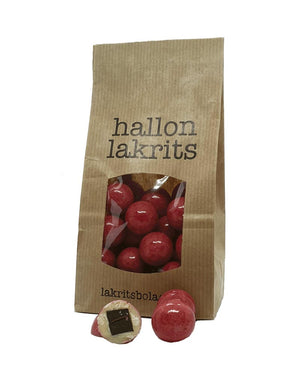 Kleine Kraftpapier-Tüte Lakritze mit Himbeere und weißer Schokolade, zeigt rote Bonbons mit schwarzem Lakritzkern und weißer Schokoladenschicht, hergestellt in Skåne, Schweden.