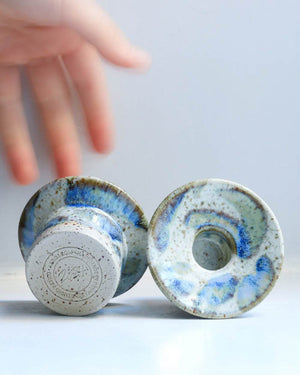 Zwei Hono Comet Rain Kerzenständer von Studio Arhoj, handgefertigt, einer zeigt den Stempel, der andere die Oberseite mit zentralem Loch, auf hellem Hintergrund.