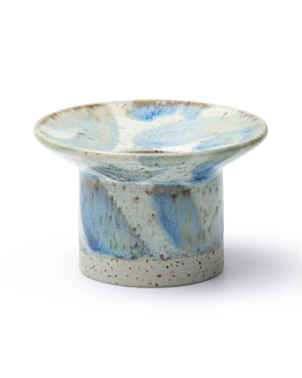 Hono Comet Rain Kerzenständer von Studio Arhoj, handgedrehtes, fußgestütztes Keramikstück mit speckeliger Glasur in sanften Blautönen, ideal für Kerzen oder dekorative Nutzung.