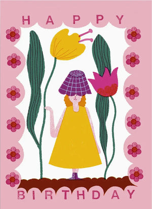 Illustration auf der Birthday Girl Postkarte zeigt eine Figur im gelben Kleid mit lila Hut, umgeben von stilisierten Blumen und einem pinken Rahmen mit HAPPY BIRTHDAY-Schriftzug.