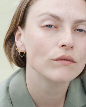 Nahaufnahme einer jungen Frau mit drei goldenen Creolen Gold Gr. M von Jukserei im Ohr, aus 24 Karat vergoldetem 925er Sterlingsilber, entworfen in Berlin.