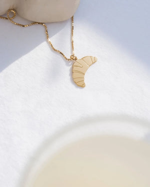 Croissant Kette Gold auf weißem Untergrund, mit zartem Croissant-Anhänger an einer 24-Karat-vergoldeten Kette. Entworfen in Berlin, handgefertigt in Italien.