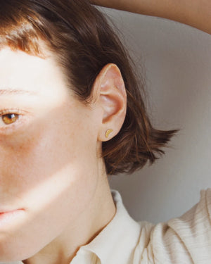 Nahaufnahme eines Croissant Ohrstecker Gold aus vergoldetem Sterlingsilber, getragen an einem Ohr. Schlichtes, elegantes Design, perfekt für einen stilvollen Akzent.