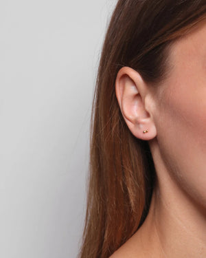 Pollen Ohrstecker Silber: Nahaufnahme eines rechten Ohrs mit zwei goldenen Kugelsteckern, schlichtes Design vom Berliner Label Jukserei, handgefertigt in Italien.