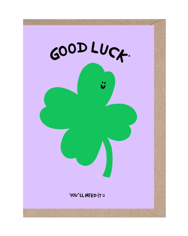 Good Luck Klappkarte mit lachendem Kleeblatt auf lila Hintergrund; humorvoller Text. Zusammenarbeit von Rumble Cards und Wobbly Studio, inklusive Umschlag. Ideal für Glückwünsche.