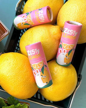 Kleine Drahtkorb mit gelben Zitronen und drei pinken Zesty Lemon Lippenbalsam-Tuben, illustriert mit Häschen und Zitrone, handgefertigt von Gustaf & Linnea.