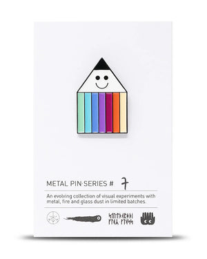 Metal Pin Penny Rainbow (Serie #7) von Studio Arhoj, mit lächelndem Gesicht und regenbogenfarbenen Pastellstreifen, auf weißer Kartenhalterung präsentiert. Maße: 2,6 x 2,8 cm.