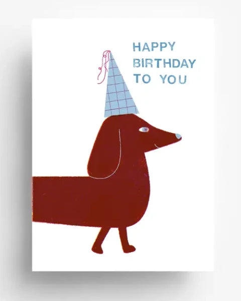 Illustration einer Geburtstagskarte Birthday Wiener Postkarte mit einem Dackel in Partyhut und HAPPY BIRTHDAY TO YOU-Text, gestaltet von Barbara Dziadosz, gedruckt auf 300g/qm Offsetpapier.