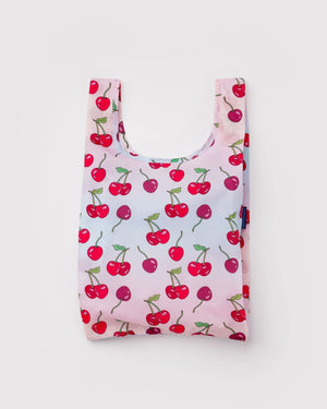 Baby Baggu Einkaufsbeutel Cherries, aus recyceltem Ripstop-Polyester, flach liegend mit roten Kirschen auf rosa Hintergrund, ideal für kleine Einkäufe und faltbar in kompakte Größe.