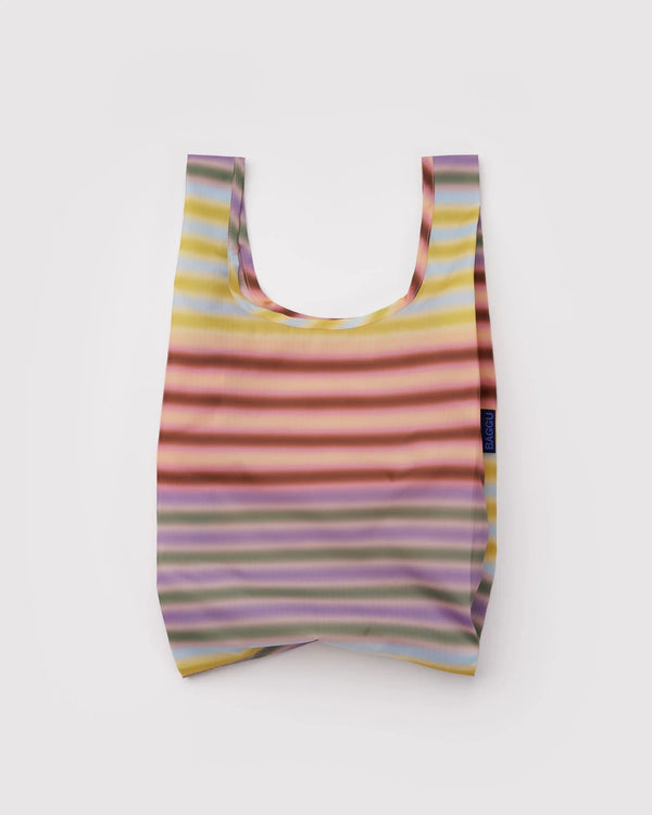 Baby Baggu Einkaufsbeutel Gradient Stripe Multi, gefaltet mit Streifendesign, zeigt geräumige Form durch ausgestreckte Griffe, aus recyceltem Ripstop-Polyester, kompakt und strapazierfähig.
