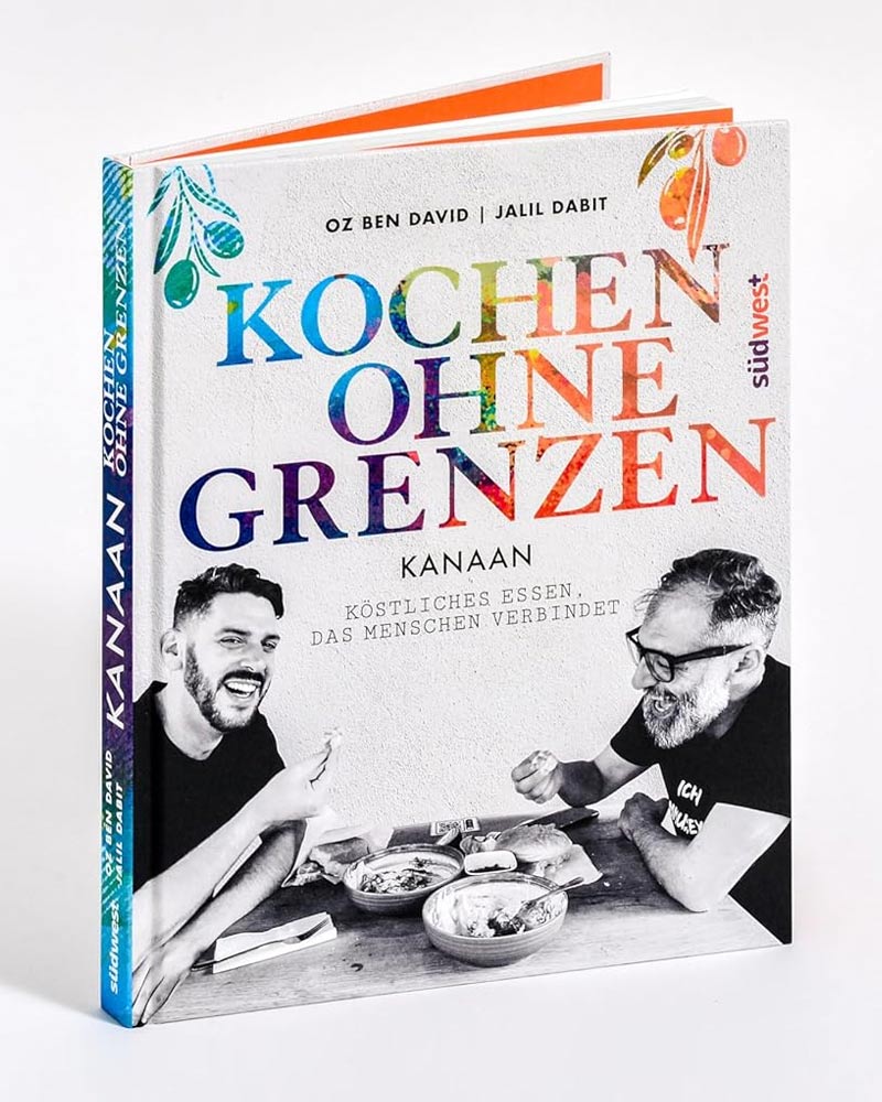 Cover von 'Kochen ohne Grenzen' mit Autoren Oz Ben David und Jalil Dabit, lachend am Tisch mit Essen. Levante-Kochbuch fördert interkulturelle Freundschaft durch gemeinsames Kochen.
