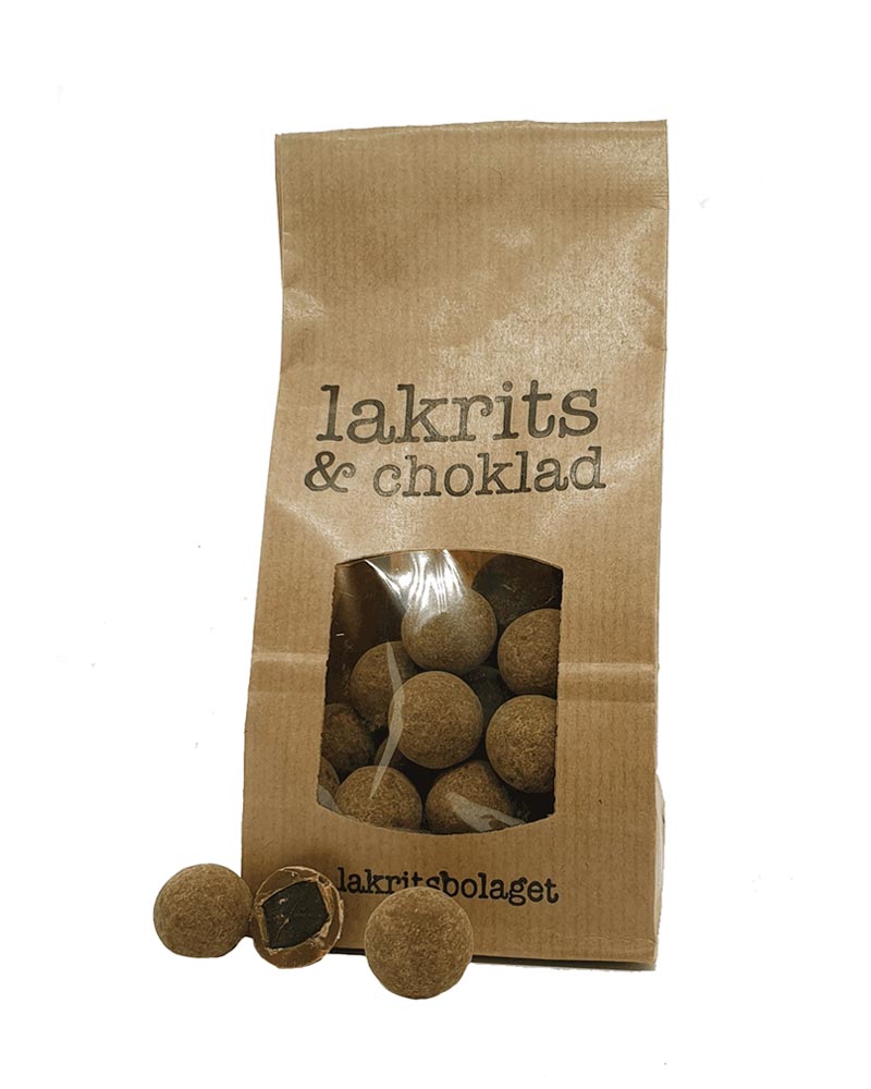 Lakritze mit Milchschokolade in einem Kraftpapierbeutel von Lakritsbolaget, durch ein Fenster sind runde Lakritzzentren in Schokoladenhülle sichtbar. Enthält Milch, Soja, Nüsse.