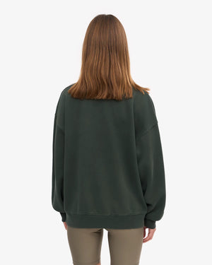 Person von hinten in einem oversized, dunkelgrünen Sweatshirt Organic Oversized Sweatshirt Midnight Forest aus Bio-Baumwolle, kombiniert mit eng anliegenden, hellbraunen Leggings.