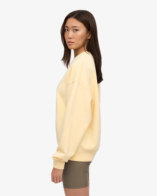 Junge Frau im Profil trägt ein Organic Oversized Sweatshirt Soft Yellow mit lockerer Passform und Bio-Baumwolle, ideal für den Alltag, präsentiert von Human Empire Shop.