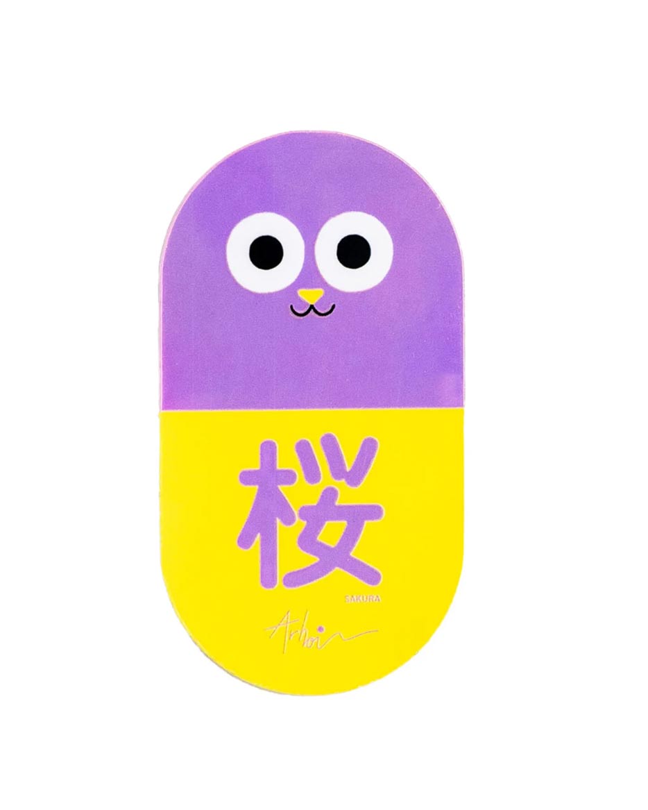 Studio Arhoj - Sticker Cat Pill Sakura: Cartoon-Katzenillustration auf einem pillenförmigen Aufkleber mit Kirschblüten-Kanji, ideal zur Verschönerung von Laptops, Flaschen oder Skateboards.
