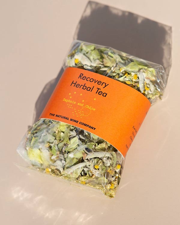 Daphnis and Chloe Recovery Herbal Tea: Klare Beuteltasche mit losen Kräutern, darunter Kamillenblüten und grüne Blätter, im Human Empire Shop erhältlich.