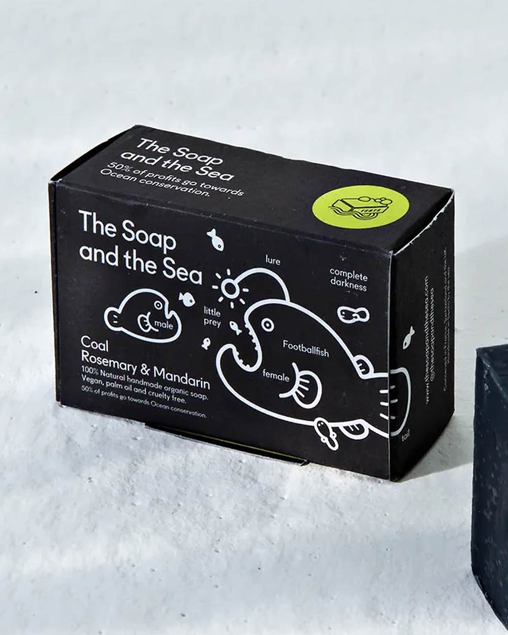 The Soap and The Sea Seife Coal, Rosemary & Mandarin: Schwarze Seifenschachtel, 100% natürlich, vegan, unterstützt Meeresschutz, handgefertigt in Spanien, mit Anglerfisch-Illustration.