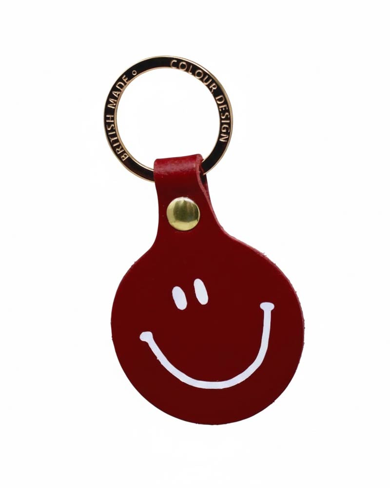 Runder roter Leder-Schlüsselanhänger Feeling Lush Smiley von Ark Colour Design, mit weißem Smiley-Gesicht und vergoldetem Ring, gefertigt in Schottland.