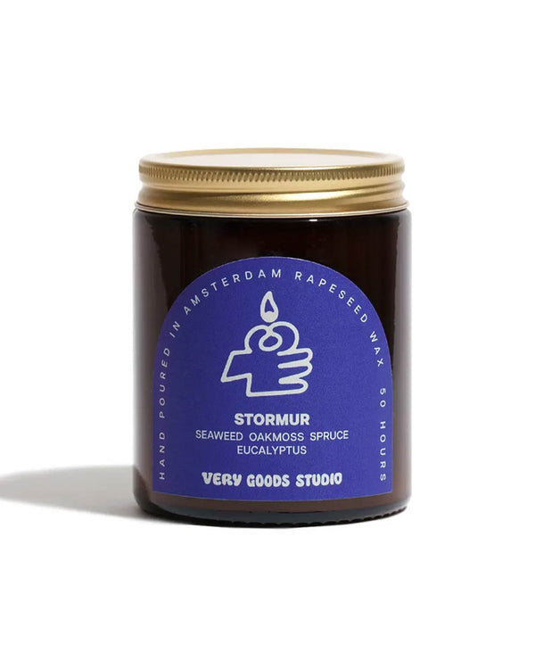 Stormur Duftkerze 170ml in dunkelbraunem Glas mit goldfarbenem Deckel, blauer Aufschrift: STORMUR, Duftnoten Meeresbrise, handgegossen in Amsterdam, Brenndauer 45-50 Stunden.