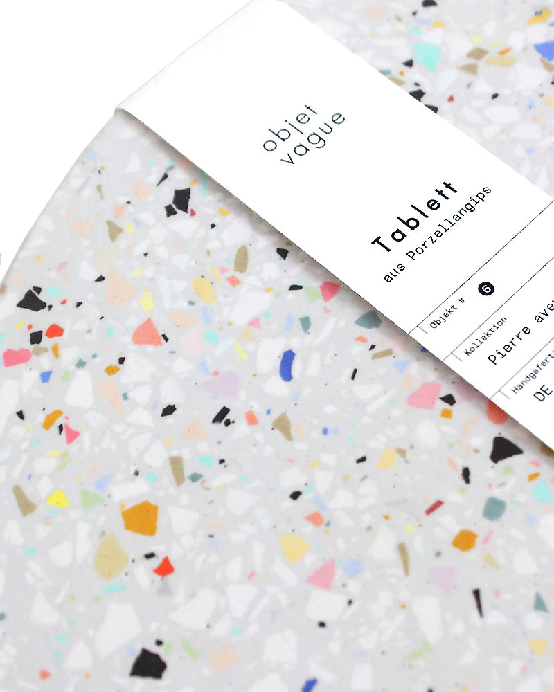 Untersetzer Terrazzo Grau XL mit bunten Stein-Chips, handgefertigt aus Porzellangips, präsentiert mit einem Papierband der Marke Objet Vague, Teil der Pierre Kollektion.