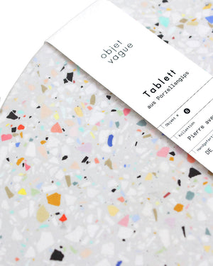Untersetzer Terrazzo Grau XL mit bunten Stein-Chips, handgefertigt aus Porzellangips, präsentiert mit einem Papierband der Marke Objet Vague, Teil der Pierre Kollektion.