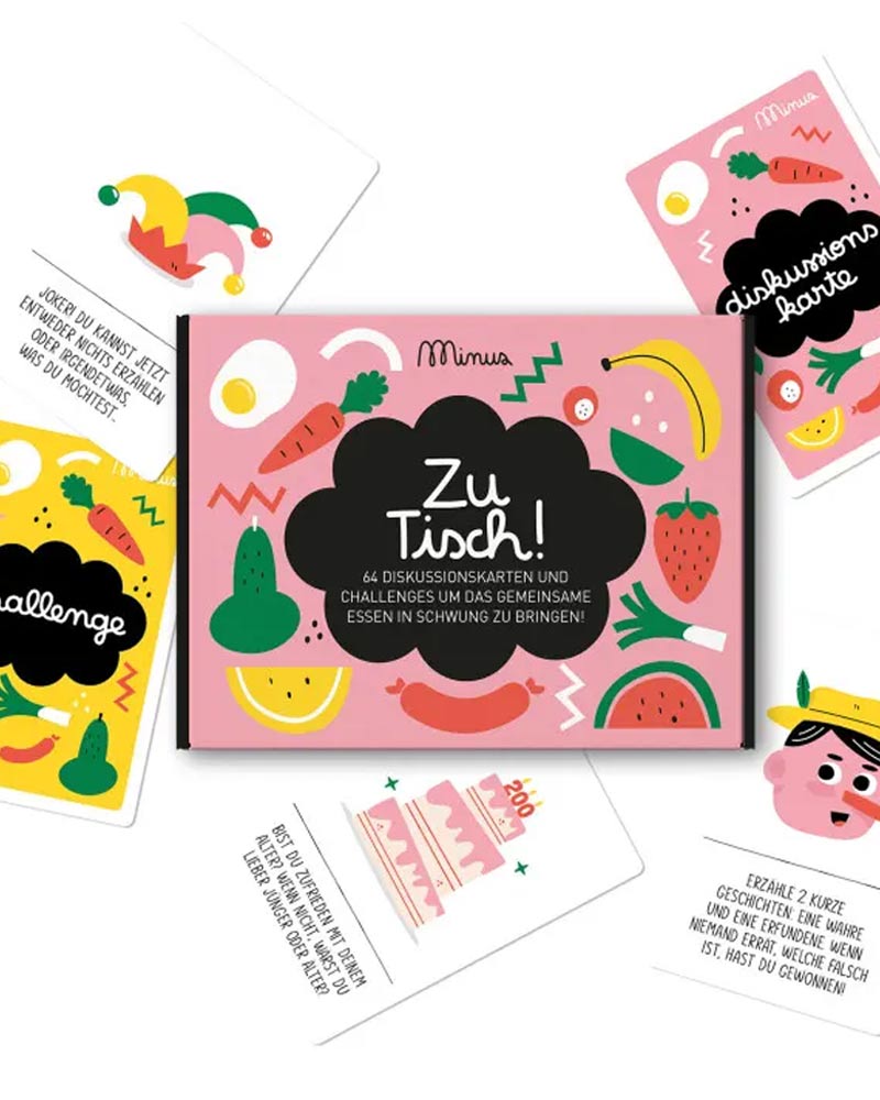 Kartenspiel Zu Tisch! in pinker Box mit fröhlichen Obst- und Gemüseillustrationen, enthält 64 Karten für Diskussionen und Herausforderungen, ideal für unterhaltsame Tischgespräche.