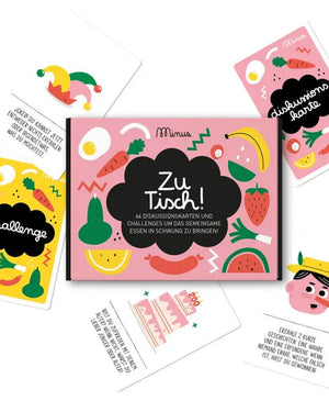 Kartenspiel Zu Tisch! in pinker Box mit fröhlichen Obst- und Gemüseillustrationen, enthält 64 Karten für Diskussionen und Herausforderungen, ideal für unterhaltsame Tischgespräche.